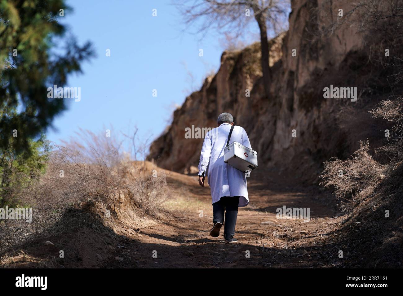210329 -- TAIYUAN, 29 marzo 2021 -- Zhang Shangbao si dirige verso un villaggio del villaggio di Tietou con il suo kit medico nella contea di Shilou, nella provincia dello Shanxi della Cina settentrionale, 23 marzo 2021. Zhang, 61 anni, che ha una sola mano, cammina per le montagne giorno dopo giorno dal 1976, salvaguardando la salute della gente del posto. Ci sono più di 600 abitanti del villaggio che vivono in 5 borghi del villaggio di Tietou nascosto tra i monti Lyuliang. In passato, era difficile accedere all'assistenza sanitaria, che aveva afflitto le masse qui per molto tempo. Nel 1976, Zhang Shangbao si diplomò in una scuola di salute all'età di 16 A. Foto Stock