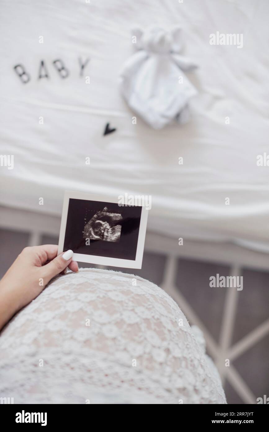 La madre che tiene in mano il feto a raggi X le chiude la pancia Foto Stock