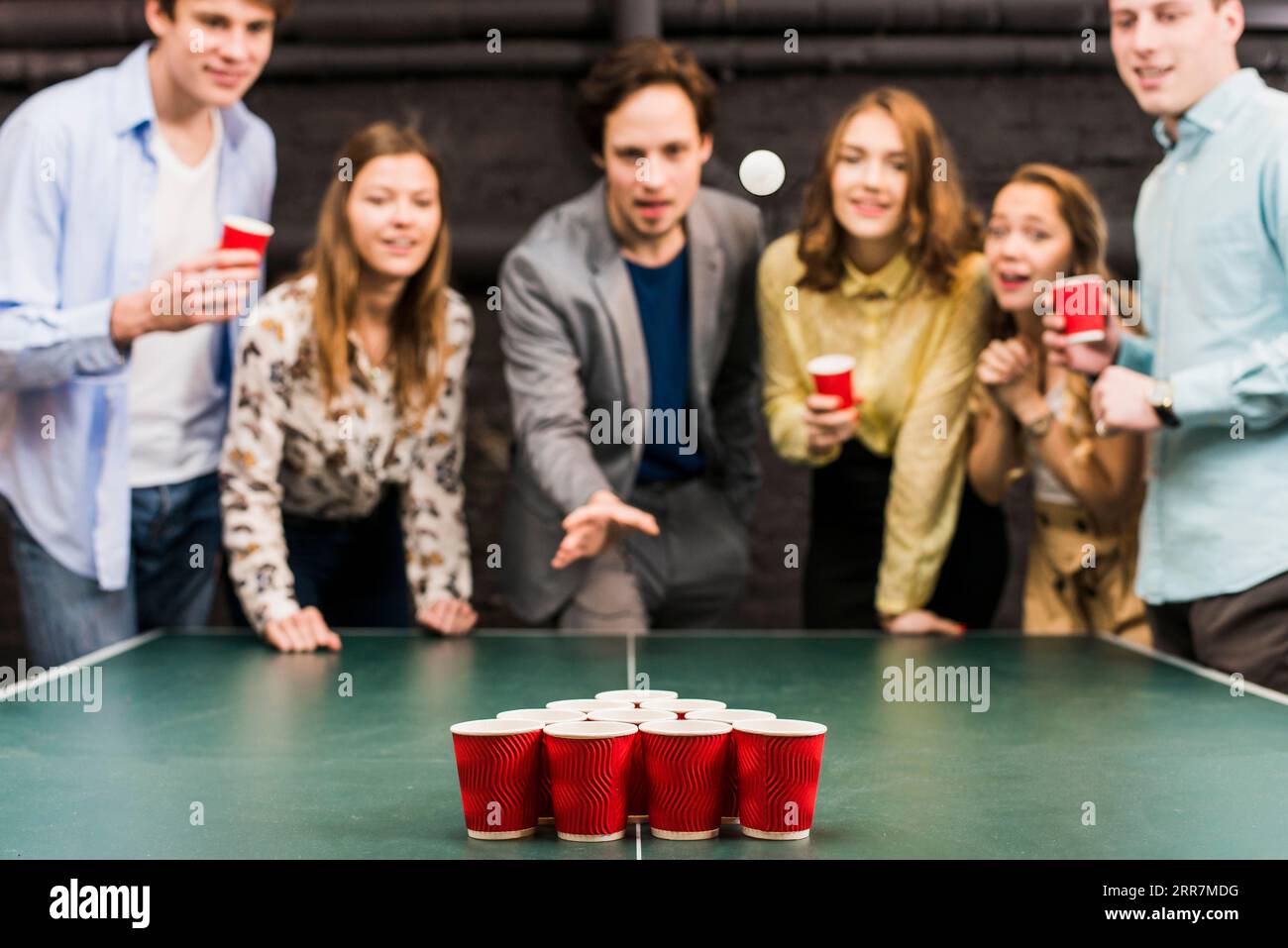 Amici che guardano la palla mentre giocano al bar beer pong Foto Stock