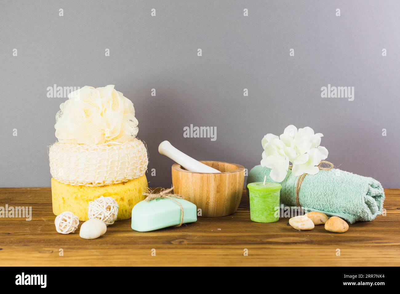 Asciugamano pietre spa loofah spugna sapone candela mortaio fiore pestello superficie in legno Foto Stock