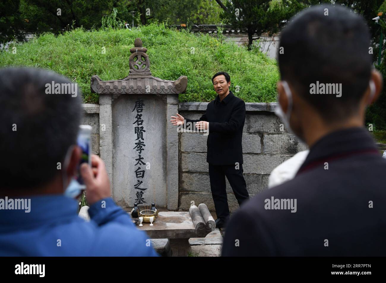 210402 -- DANGTU, 2 aprile 2021 -- GU Changxin presenta la tomba di li Bai ai turisti al parco culturale li Bai, nella contea di Dangtu della città di Maanshan, nella provincia di Anhui della Cina orientale, 1 aprile 2021. La tomba di li Bai, un famoso poeta della dinastia Tang 618-907, si trova ai piedi del monte Qingshan nella contea di Dangtu nella città di Maanshan. Dopo la morte di li Bai a Dangtu, il suo buon amico GU Lanxin offrì la sua terra come luogo di sepoltura di li Bai. Da allora, la famiglia GU è diventata custode della tomba di li Bai, che continua ancora oggi. Nel 1985, il diciottenne GU Changxin divenne il custode di tombe della 49a generazione. Per Foto Stock