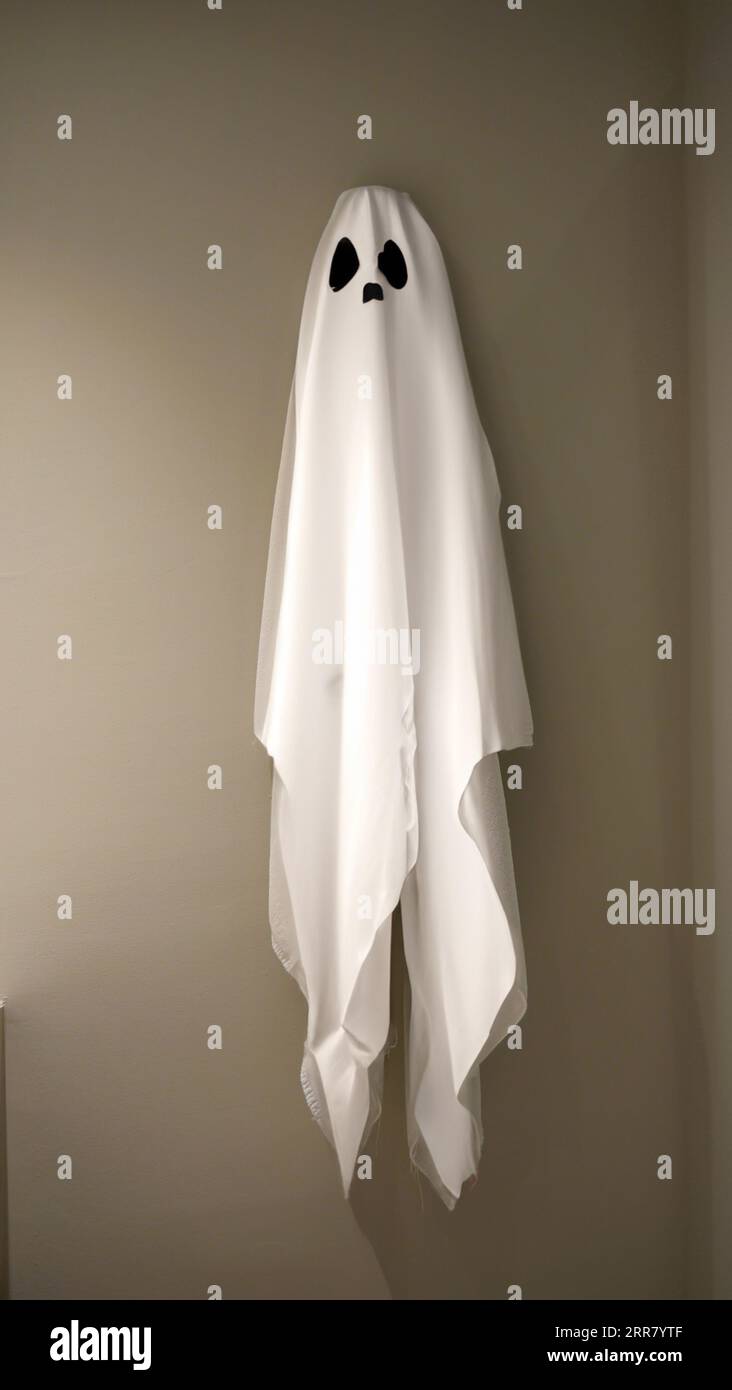 Un vestito bianco coperto da fantasmi è stato appeso al gancio al muro, rompere il tempo, fare una pausa, divertente concetto di Halloween, costume da festa, h Foto Stock