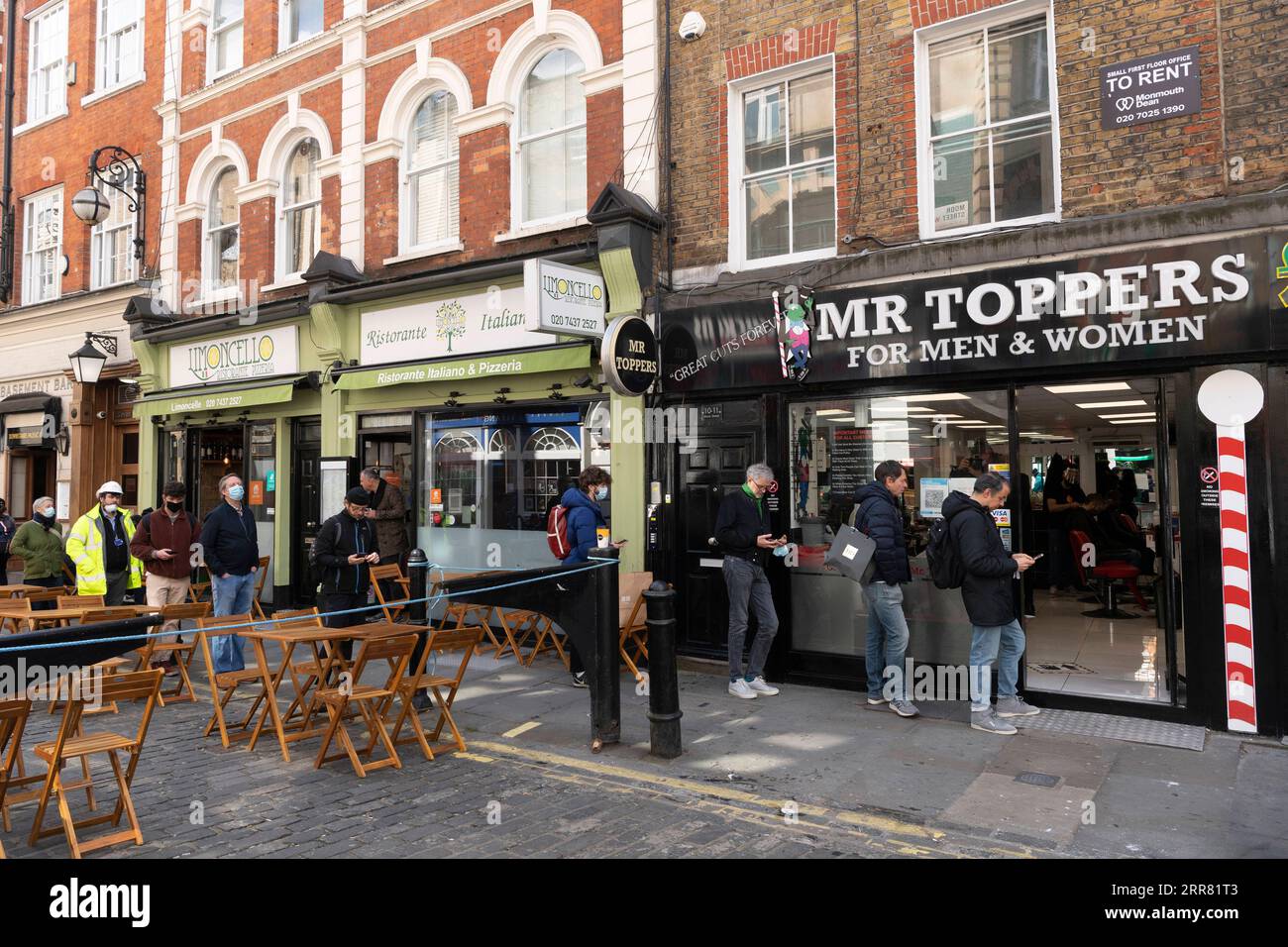 210413 -- LONDRA, 13 aprile 2021 -- la gente fa la fila fuori da un barbiere a Soho a Londra, in Gran Bretagna, 12 aprile 2021. In Inghilterra, tutti i negozi riaprono da lunedì, oltre a parrucchieri, saloni di bellezza e altri servizi a stretto contatto. Ristoranti e pub sono autorizzati a servire cibo e alcolici ai clienti seduti all'aperto. Nel frattempo, palestre, centri termali, zoo, parchi a tema, le biblioteche e i centri di comunità possono essere aperti. Foto di /Xinhua UK-COVID-19-LOCKDOWN-EASE RayxTang PUBLICATIONxNOTxINxCHN Foto Stock