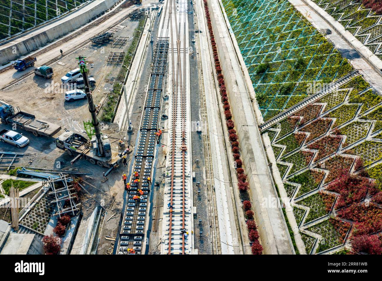 210413 -- NANZHANG, 13 aprile 2021 -- foto aerea scattata il 12 aprile 2021 mostra i lavoratori che lavorano sui binari senza palla nel cantiere della stazione di Nanzhang della ferrovia ad alta velocità Zhengzhou-Wanzhou nella contea di Nanzhang, nella provincia centrale di Hubei della Cina. Con una velocità progettata di 350 km all'ora, la ferrovia Zhengzhou-Wanzhou, che collega Zhengzhou nella provincia di Henan della Cina centrale e Wanzhou nel sud-ovest di Chongqing della Cina, è una parte importante dei sistemi ferroviari nelle due regioni. Rispetto ai cingoli tradizionali, il cingolo senza ballastless ha una durata maggiore e richiede meno sforzo i. Foto Stock