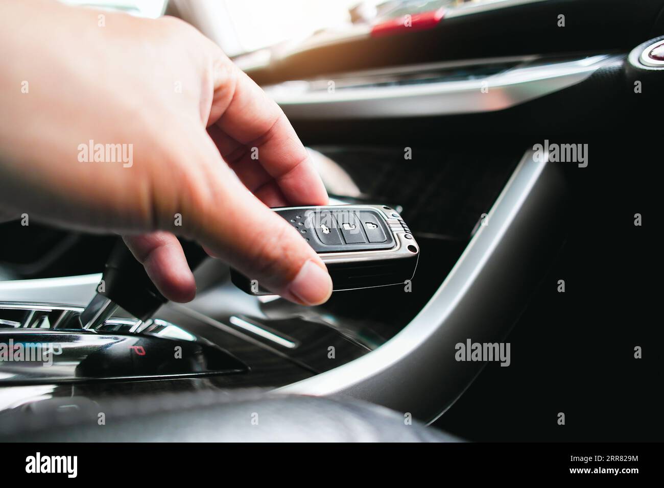 Primo piano di una mano del conducente che tiene un'auto con il telecomando in un'auto, il conducente avvia il motore con un telecomando di un sistema di avviamento del motore senza chiavi Foto Stock