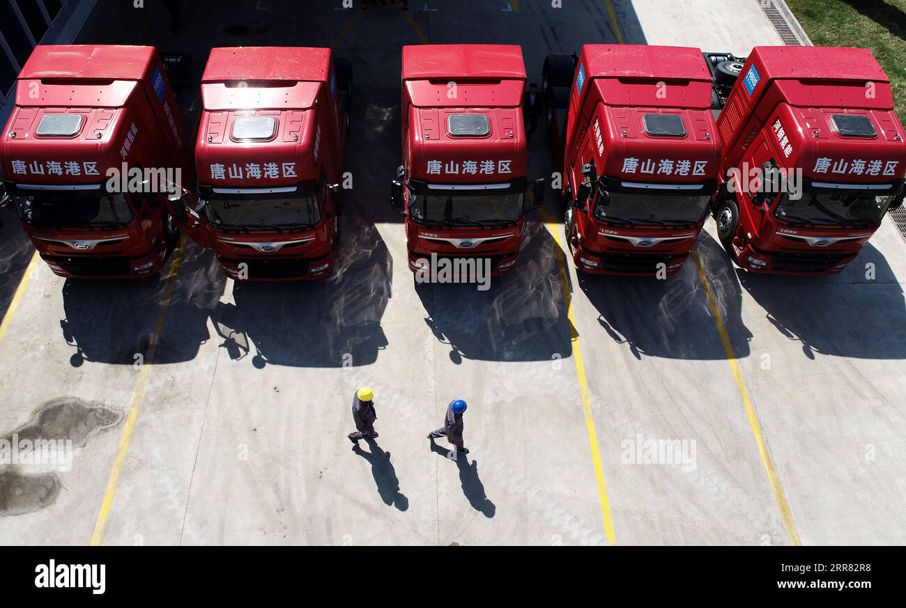 210414 -- TANGSHAN, 14 aprile 2021 -- la foto scattata con un drone mostra i lavoratori che camminano davanti a cinque camion pesanti alimentati a idrogeno di recente introduzione nella zona di sviluppo economico di Tangshan Haigang a Tangshan, nella provincia di Hebei nella Cina settentrionale, 14 aprile 2021. Mercoledì sono stati introdotti cinque camion pesanti alimentati a idrogeno dalla zona di sviluppo economico di Tangshan Haigang. La flotta di veicoli industriali è tra i primi tentativi della zona di ottimizzare la struttura industriale e il consumo energetico sostituendo gradualmente il carburante diesel con le celle di alimentazione a idrogeno più ecologiche. CHINA-HEBEI-TANGSH Foto Stock