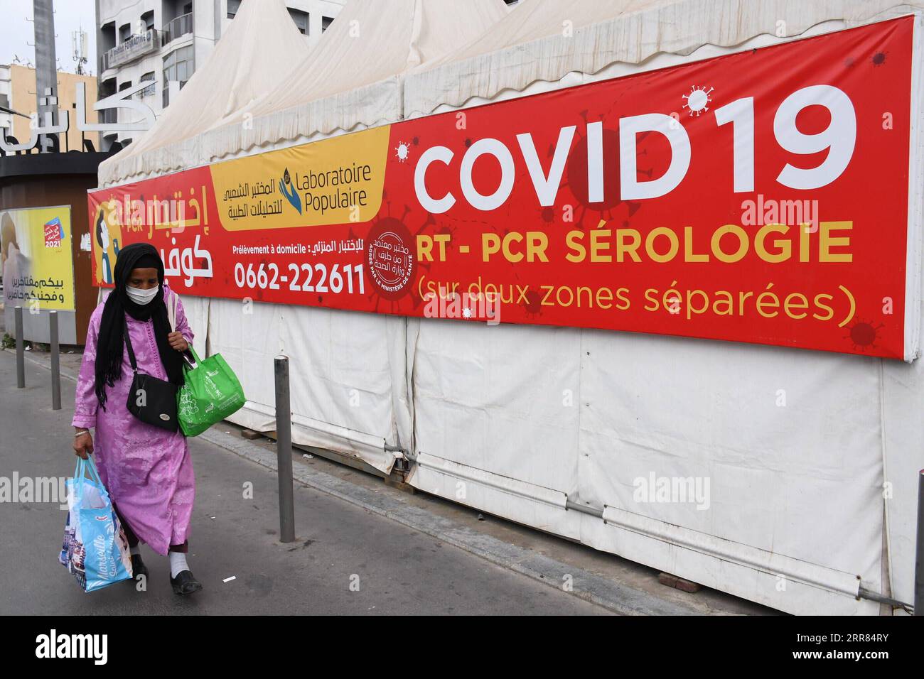 210417 -- CASABLANCA MAROCCO, 17 aprile 2021 -- Una donna che indossa una maschera cammina davanti a uno striscione di test COVID-19 a Casablanca, Marocco, il 17 aprile 2021. Il numero di casi COVID-19 del Marocco è salito a 505.447 sabato, in quanto sono stati registrati 600 nuovi casi nelle ultime 24 ore. Foto di /Xinhua MOROCCO-CASABLANCA-COVID-19-CASES Chadi PUBLICATIONxNOTxINxCHN Foto Stock