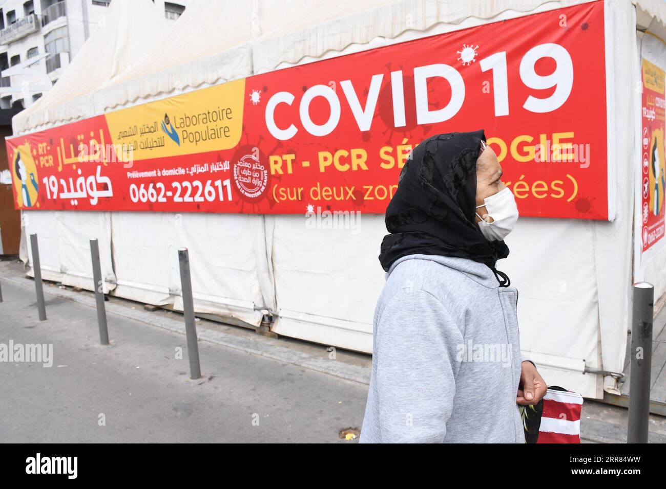 210417 -- CASABLANCA MAROCCO, 17 aprile 2021 -- Una donna che indossa una maschera cammina davanti a uno striscione di test COVID-19 a Casablanca, Marocco, il 17 aprile 2021. Il numero di casi COVID-19 del Marocco è salito a 505.447 sabato, in quanto sono stati registrati 600 nuovi casi nelle ultime 24 ore. Foto di /Xinhua MOROCCO-CASABLANCA-COVID-19-CASES Chadi PUBLICATIONxNOTxINxCHN Foto Stock