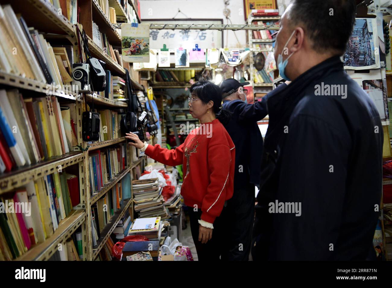 210422 -- HEFEI, 22 aprile 2021 -- Chen Guixia 1st L raccoglie libri per un cliente alla Zengzhi Bookshop di Hefei, provincia di Anhui, Cina orientale, 19 aprile 2021. Sin dalla sua apertura, 21 anni fa, la Zengzhi Bookshop, un rivenditore di libri di seconda mano non descritto nel centro di Hefei, è stata salutata come un punto di riferimento intellettuale tra gli appassionati di libri locali. Il suo defunto proprietario, Zhu Chuanguo, vantava una collezione di 000 libri usati, tutti acquistati da lettori ordinari e centri di riciclaggio. Sotto la visione di Zhu, i libri di scarto possono rivelarsi illuminanti per qualcun altro che merita quindi una r Foto Stock