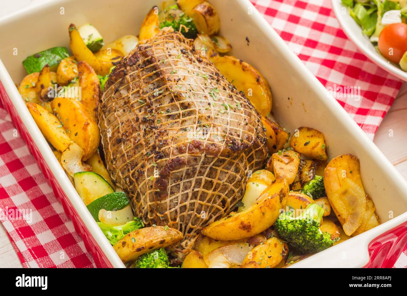 Arrosto di maiale in un piatto con patate, zucchine e broccoli Foto Stock