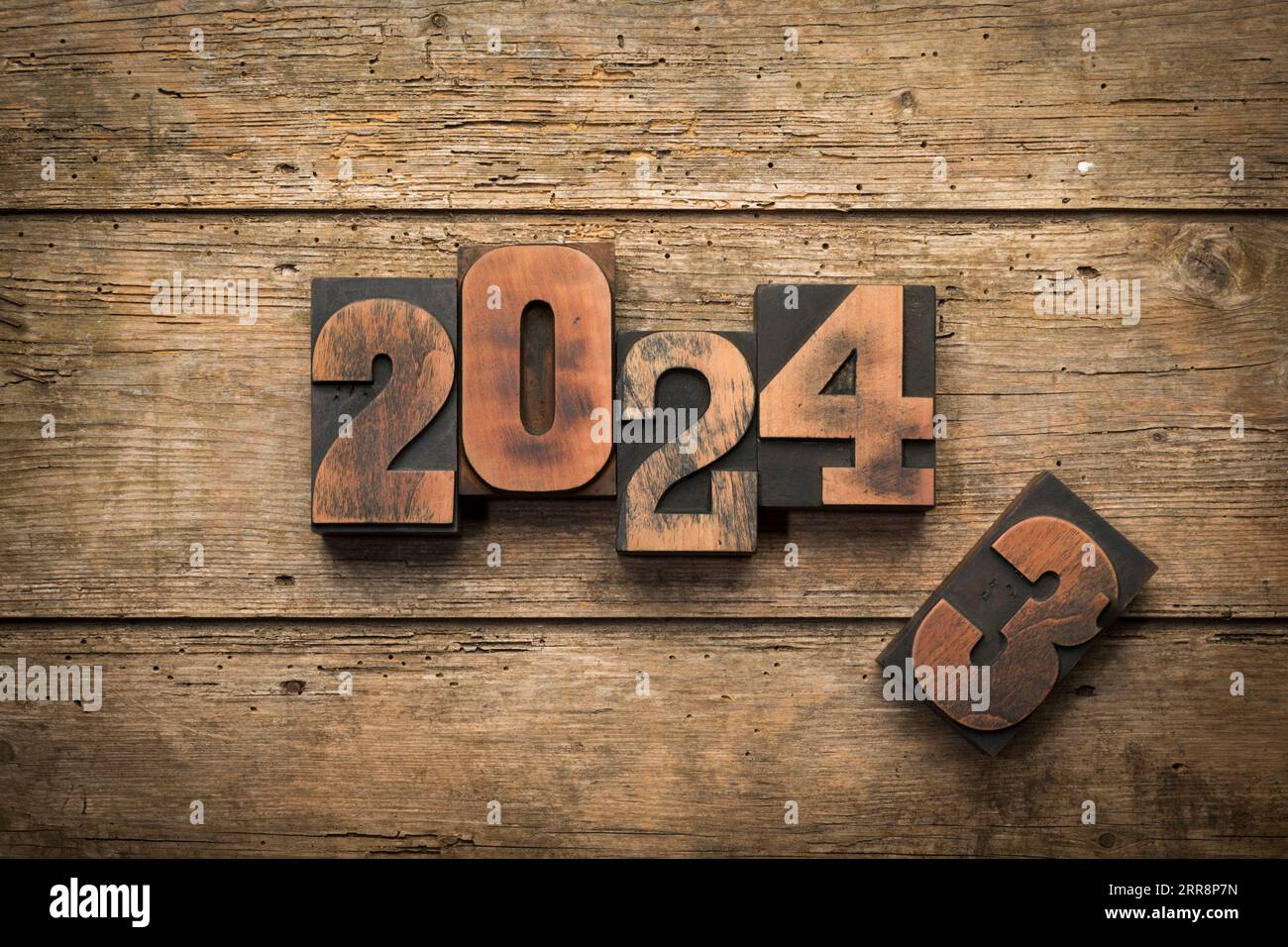 Passaggio dall'anno 2023 al 2024 scritto con blocchi di stampa vintage su sfondo rustico in legno Foto Stock