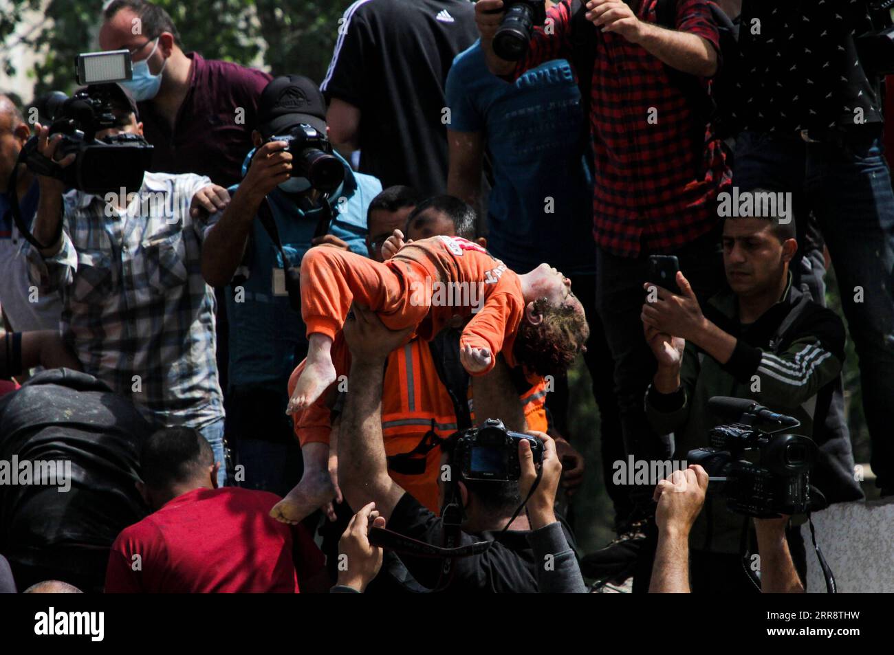 210518 -- GAZA/GERUSALEMME, 18 maggio 2021 -- Un uomo palestinese tiene in braccio un bambino che è stato salvato dalle macerie di case distrutte a seguito di attacchi aerei israeliani in al-Wahda Street, nel centro di Gaza, il 16 maggio 2021. Foto di /Xinhua Xinhua titoli: Con il conflitto Palestina-Israele intensificato, il coraggio e la coscienza necessari per raggiungere la pace RizekxAbdeljawad PUBLICATIONxNOTxINxCHN Foto Stock