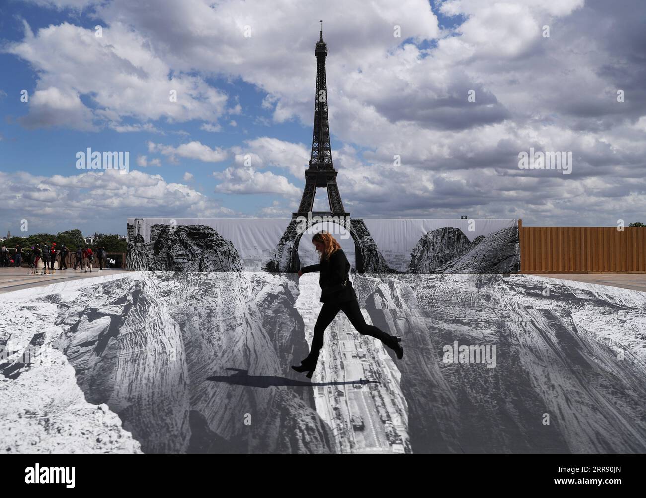 210521 -- PARIGI, 21 maggio 2021 -- Una donna posa per le foto in piazza Trocadero vicino alla Torre Eiffel, dove l'artista e fotografo francese conosciuto come JR ha allestito le sue opere, a Parigi, in Francia, il 21 maggio 2021. FRANCIA-PARIGI-TORRE EIFFEL-STREET ART GAOXJING PUBLICATIONXNOTXINXCHN Foto Stock