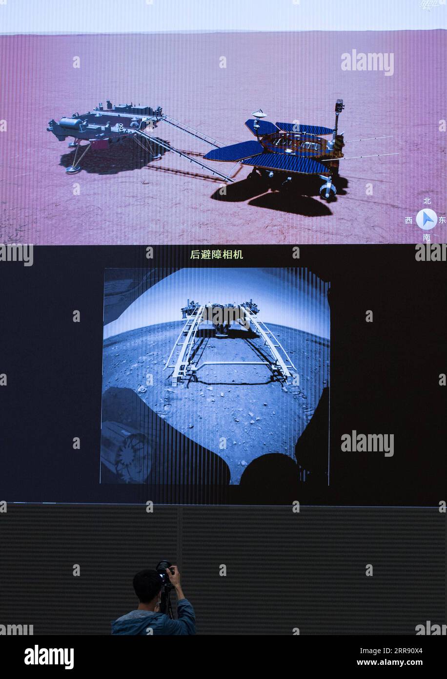 210522 -- PECHINO, 22 maggio 2021 -- Un membro dello staff registra il processo del primo rover Marte cinese, Zhurong, che scende dalla sua piattaforma di atterraggio alla superficie marziana dallo schermo del Beijing Aerospace Control Center di Pechino, capitale della Cina, 22 maggio 2021. Il primo rover marziano della Cina, Zhurong, è sceso dalla piattaforma di atterraggio alla superficie marziana sabato, lasciando le prime impronte del paese sul pianeta rosso. La prima unità di successo di Zhurong ha reso la Cina il secondo paese dopo gli Stati Uniti ad atterrare e gestire un rover su Marte. EYESONSCI CHINA-BEIJING-MARS ROVER-DRIVE C. Foto Stock