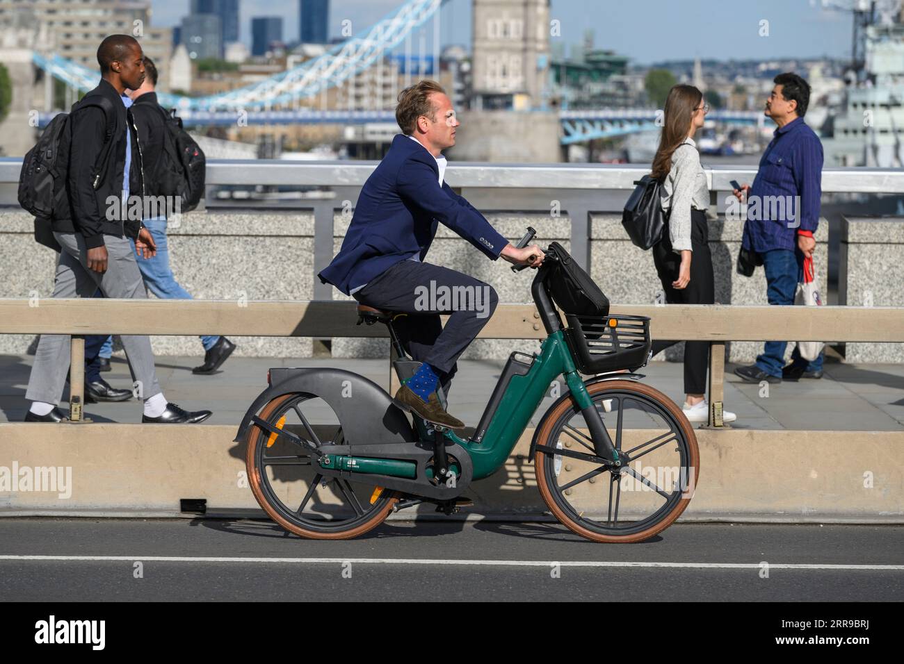 Un uomo che viaggia su una bicicletta elettrica HumanForest attraverso il London Bridge, durante l'ora di punta. London Bridge, Londra, Regno Unito. 17 luglio 2023 Foto Stock