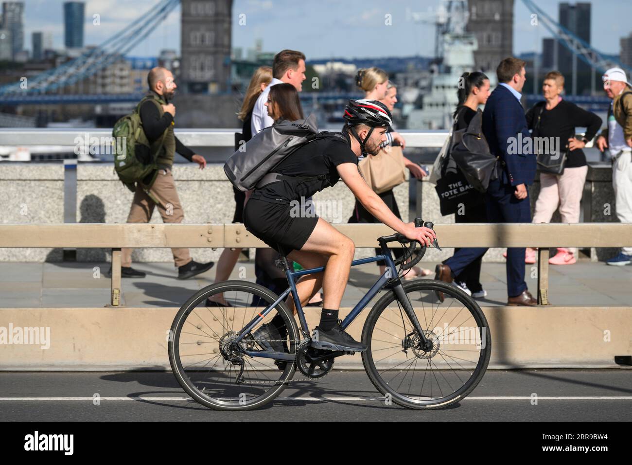 Un uomo che viaggia in bicicletta durante l'ora di punta attraverso il London Bridge, Londra, Regno Unito. 17 luglio 2023 Foto Stock