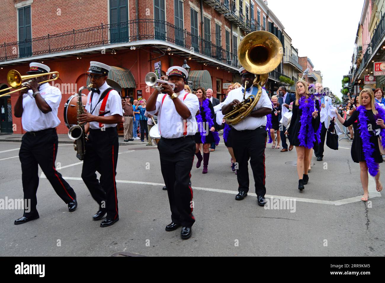 Una seconda marcia di musicisti jazz conduce i festeggiatori attraverso il quartiere francese di New Orleans Foto Stock