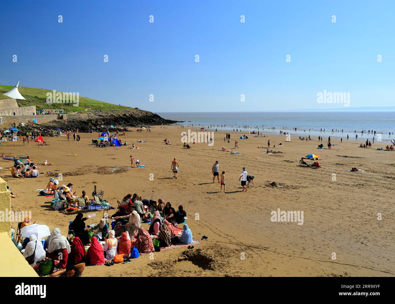 Gruppi di donne di minoranze etniche che amano visitare la spiaggia, Whitmore Bay, Barry Island, vale of Glamorgan, South Wales, REGNO UNITO. Foto Stock
