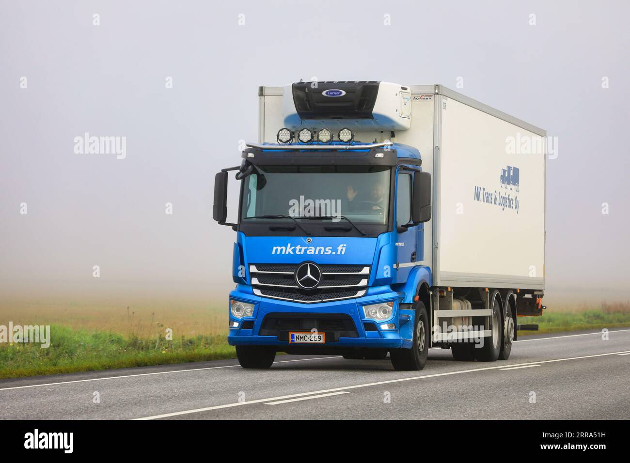 Il rimorchio di trasporto refrigerato Mercedes-Benz blu trasporta le merci lungo l'autostrada 52 in una mattinata estiva nebbiosa. Salo, Finlandia. 25 agosto 2023. Foto Stock