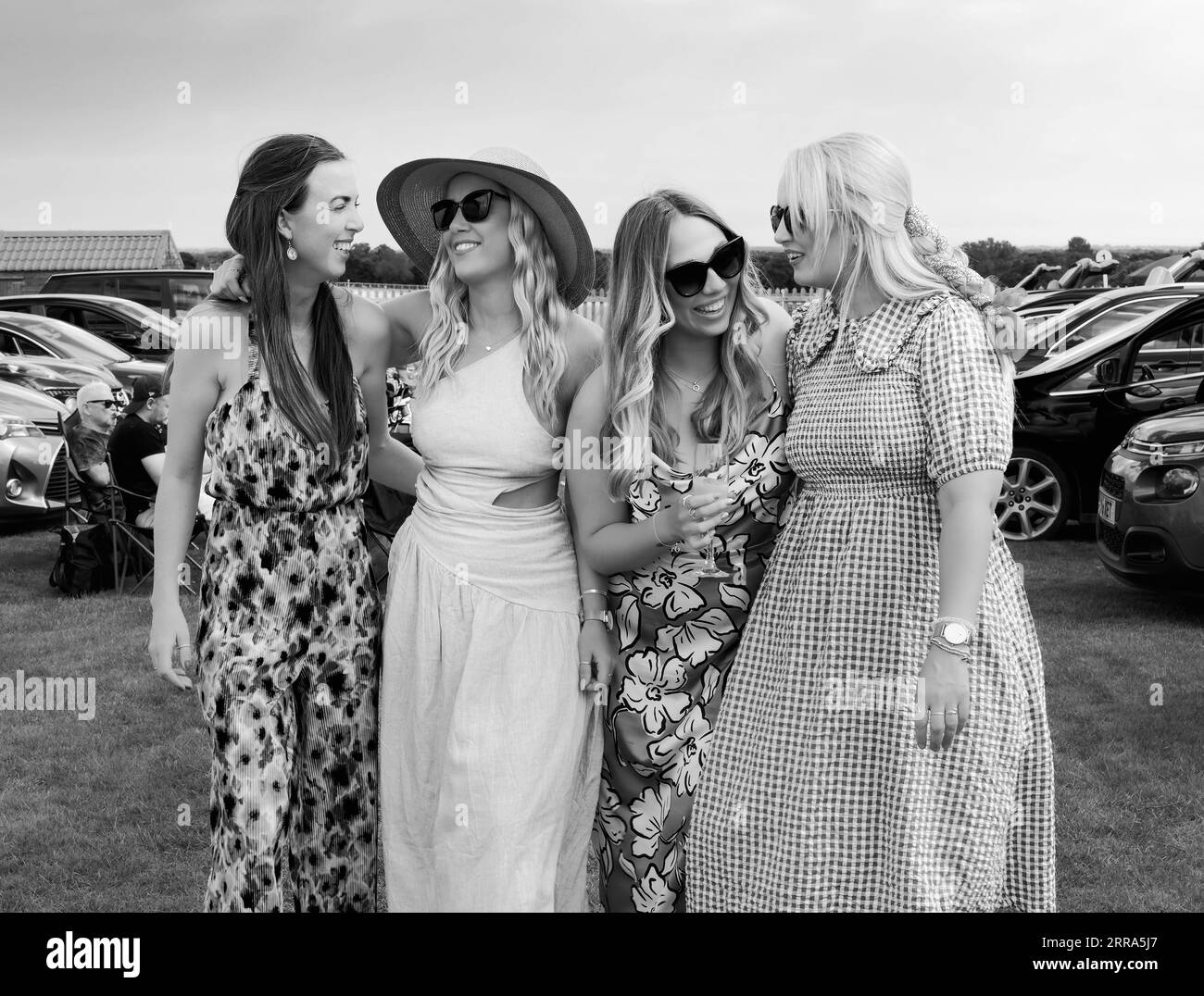 Gruppo di quattro donne che ridono e sorridono e vestite con abiti colorati goditi il Ladies Day alle corse di Beverley, Regno Unito. Foto Stock