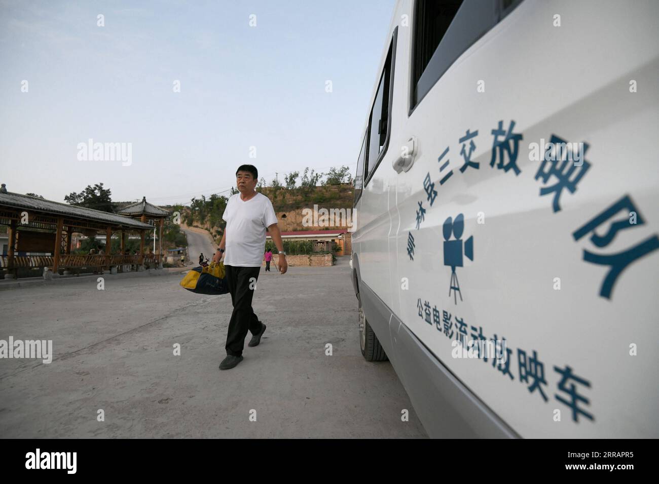 210813 -- TAIYUAN, 13 agosto 2021 -- Liu Bufei cammina davanti a un'auto di proiezione mobile con lo schermo in mano nel villaggio di Gaojiayan, Sanjiao Township della contea di Liulin, provincia di Shanxi nella Cina settentrionale, 10 agosto 2021. Nel 1975, Sanjiao Township ha istituito un team di proiezione cinematografica. Liu Bufei e Liu Dengzhao, entrambi cinefili fin dall'infanzia, si unirono alla squadra e divennero proiettisti rurali. Nel 2007, il team è diventato una troika quando si è Unito al proiettile di seconda generazione Xue Xiaogang, che aveva visto film all'aperto nel villaggio mentre cresceva. Nel corso degli anni, il team di proiezione, per innumer Foto Stock