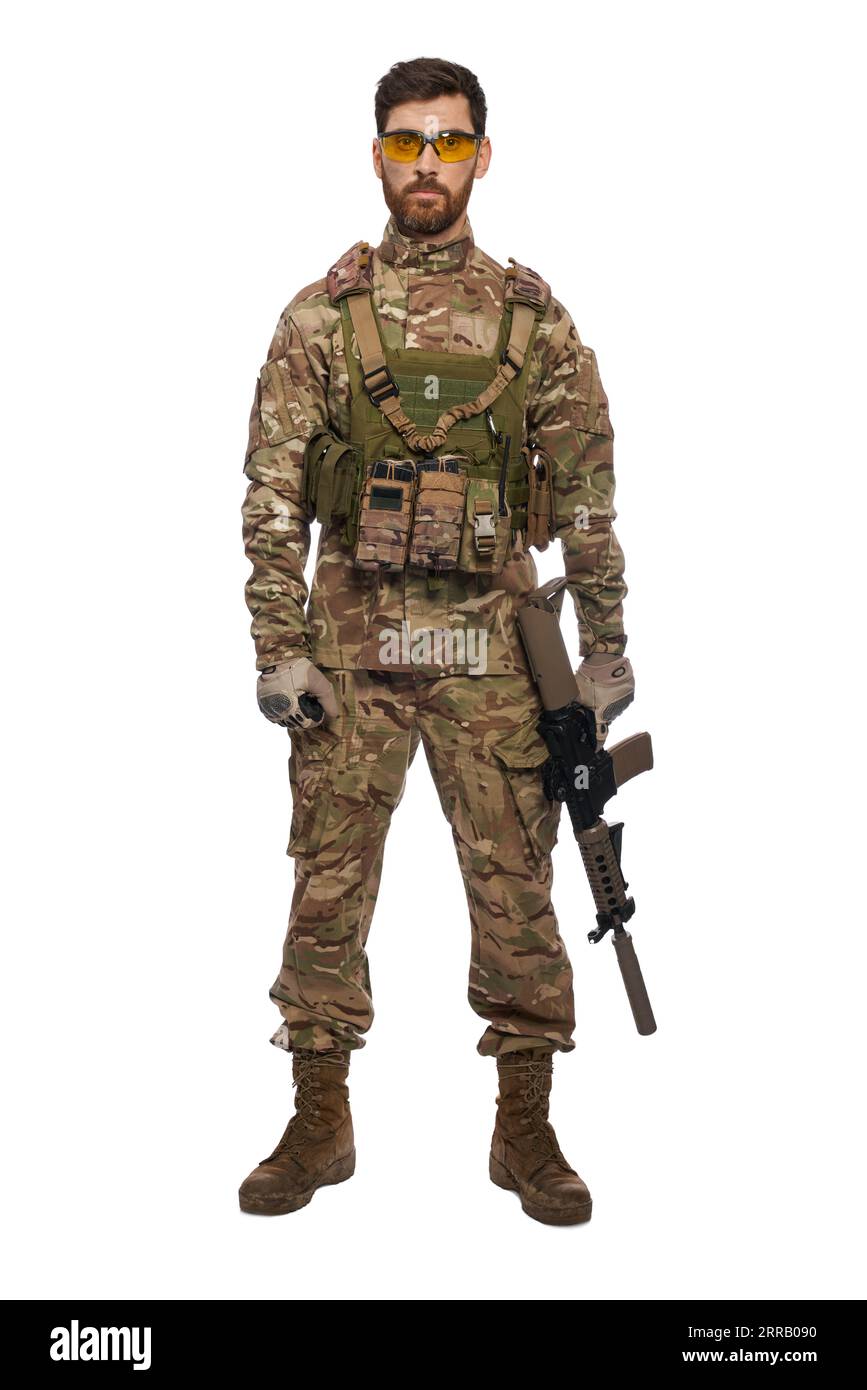 Seri soldato maschio con mitragliatrice in mano, che guarda la macchina fotografica in studio. Vista frontale di un potente trooper in armatura che posa, regge un'arma, isolato su sfondo bianco. Concetto di forza militare. Foto Stock