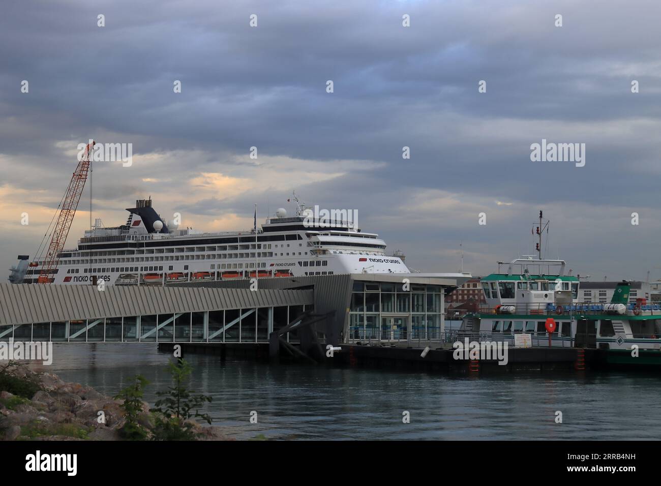 Enorme nave da crociera che sovrasta il traghetto e il pontone di Gosport. Vasco da Gama è una nave da crociera classe S di proprietà di Mystic Invest e gestita dalla società tedesca Nicko Cruises. I nomi precedenti sono Statendam e Pacific Eden. Attualmente è registrata al porto di Madeira in Portogallo e prende il nome dall'esploratore portoghese. La nave ha quattordici ponti e può trasportare 1258 passeggeri e 557 membri dell'equipaggio. Foto Stock