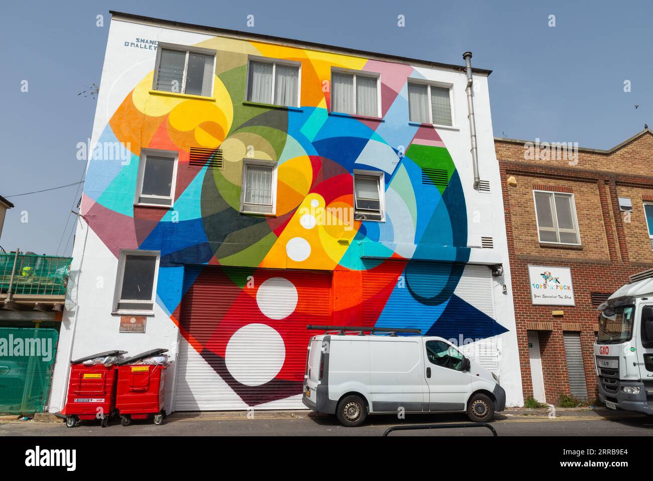 Parte dell'evento di arte dei graffiti Southend City Jam intorno a Southend on Sea, Essex, Regno Unito. Parete della proprietà dipinta in modo luminoso, con scena di una strada posteriore Foto Stock