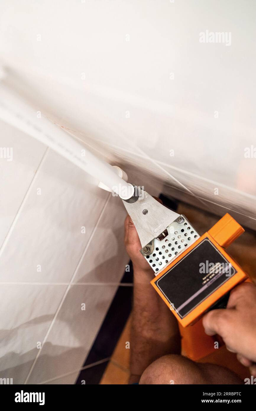 l'idraulico si adatta al tubo in polipropilene con saldatore nell'angolo del bagno durante l'installazione di nuove tubazioni Foto Stock