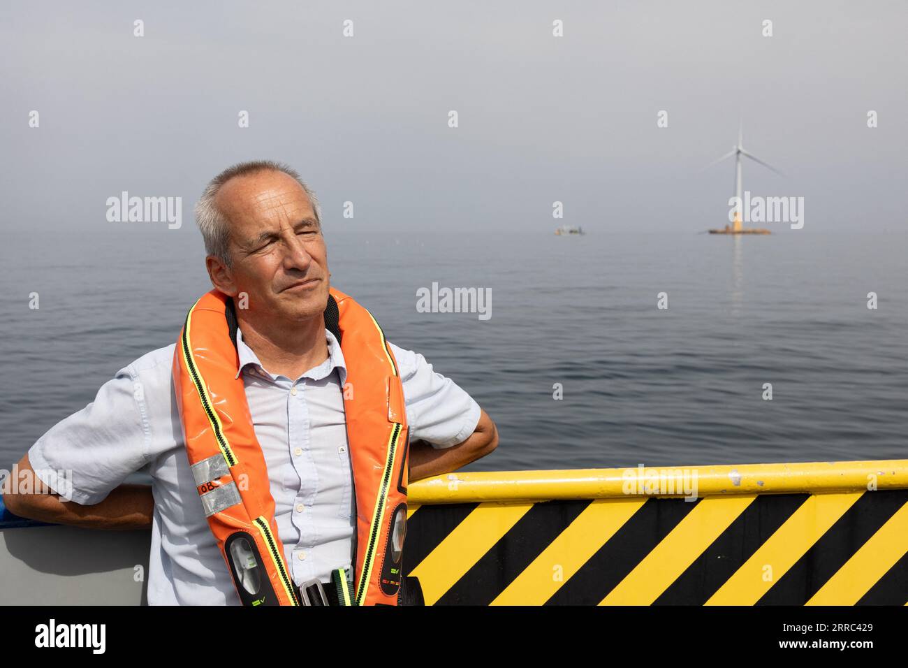 Le Croisic, Francia. 7 settembre 2023. Il direttore della Fondation apre C Bertrand Alessandrini su una barca accanto all'unità di produzione galleggiante di idrogeno Lhyfe accanto alla turbina eolica galleggiante Floatgen, presso il sito di sperimentazione SEM-Rev al largo di le Croisic, Francia occidentale, il 7 settembre 2023. Foto di Raphael Lafargue/ABACAPRESS.COM Credit: Abaca Press/Alamy Live News Foto Stock