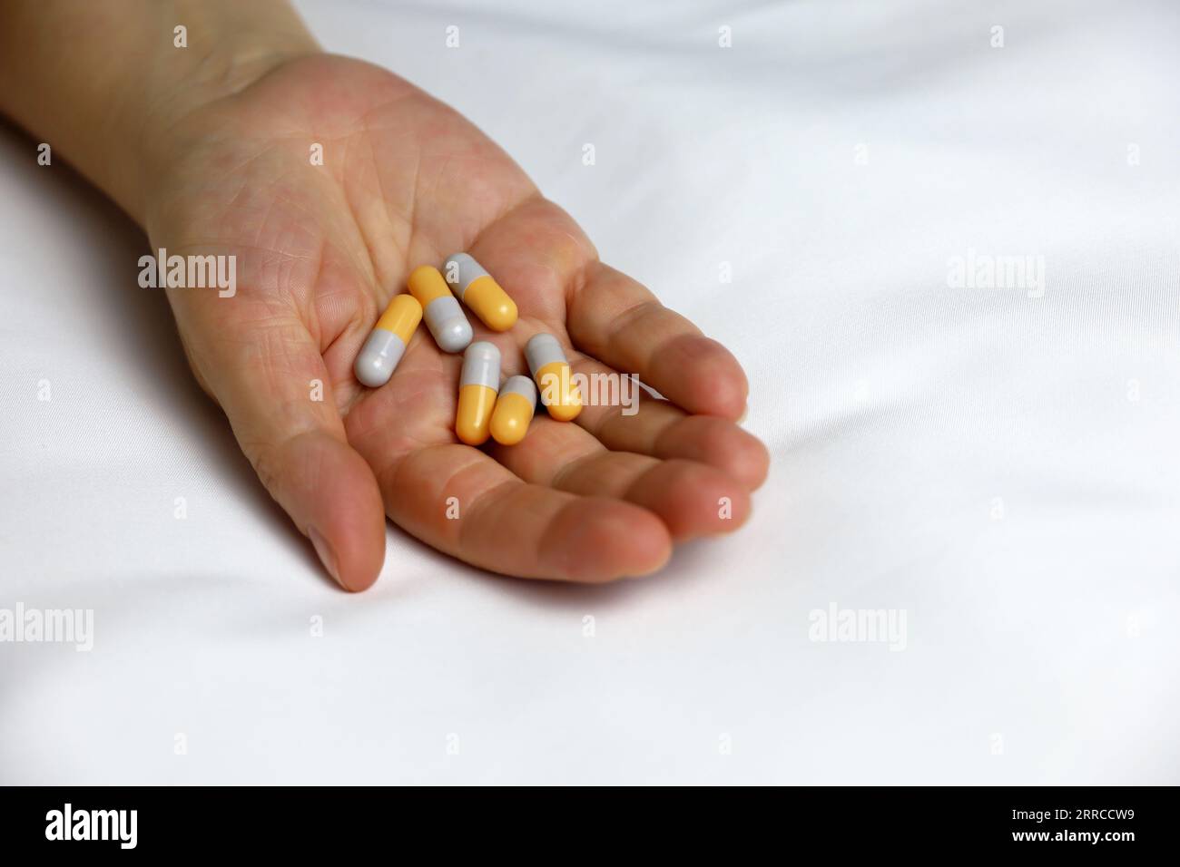 Pillole in un palmo di mano femminile sul letto. Concetto di farmaco, vitamine o pillola del sonno Foto Stock