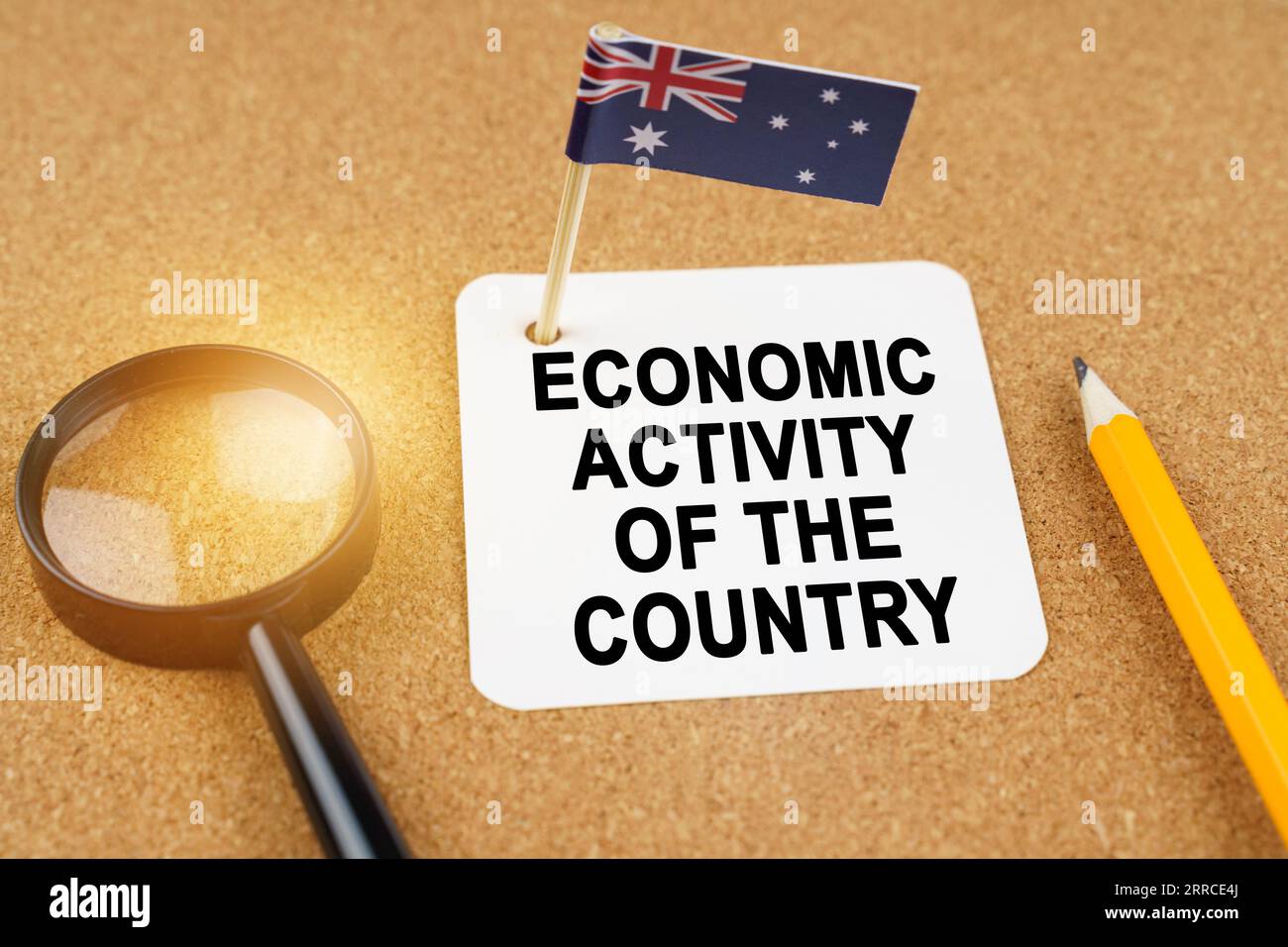 Economia e finanza. Sul tavolo ci sono una lente d'ingrandimento, una matita, la bandiera dell'Australia e un foglio di carta con l'iscrizione - economico Foto Stock