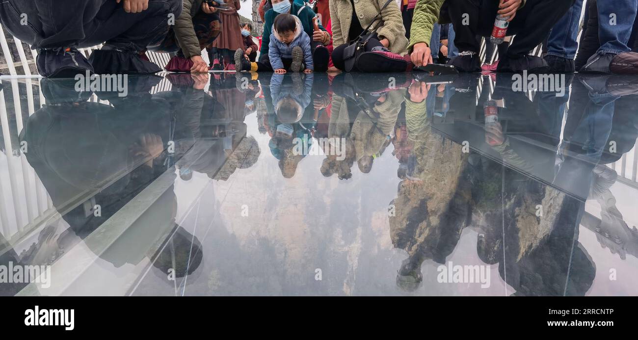 211112 -- ZHANGJIAJIE, 12 novembre 2021 -- i turisti guardano attraverso un ponte con fondo in vetro al Grand Canyon di Zhangjiajie, nella provincia centrale di Hunan della Cina, il 12 novembre 2021. Il ponte lungo 430 metri e largo sei metri, che collega due scogliere ripide a 300 metri dal suolo, è pavimentato con 99 pannelli di vetro trasparente a tre strati. CHINA-HUNAN-ZHANGJIAJIE-GLASS BRIDGE CN ZHAOXZHONGZHI PUBLICATIONXNOTXINXCHN Foto Stock