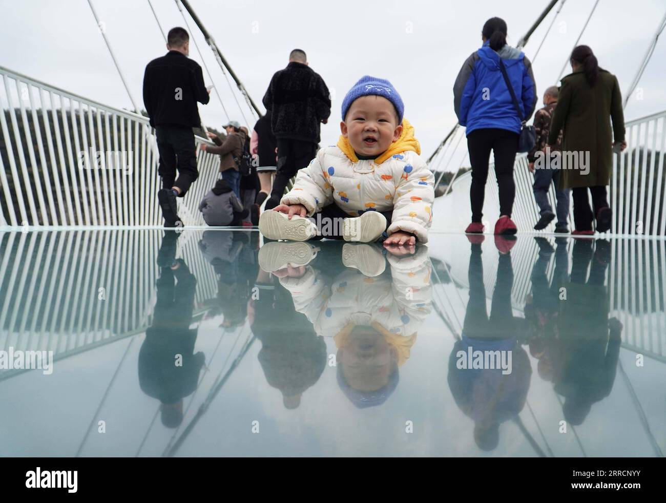 211112 -- ZHANGJIAJIE, 12 novembre 2021 -- Un bambino siede su un ponte con fondo in vetro al Grand Canyon di Zhangjiajie, nella provincia centrale di Hunan, in Cina, il 12 novembre 2021. Il ponte lungo 430 metri e largo sei metri, che collega due scogliere ripide a 300 metri dal suolo, è pavimentato con 99 pannelli di vetro trasparente a tre strati. CHINA-HUNAN-ZHANGJIAJIE-GLASS BRIDGE CN ZHAOXZHONGZHI PUBLICATIONXNOTXINXCHN Foto Stock