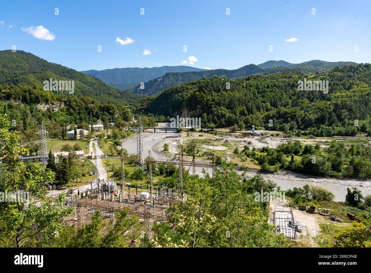 Trasformatore ad alta tensione per campo elettrico con linee e pali in montagna Foto Stock