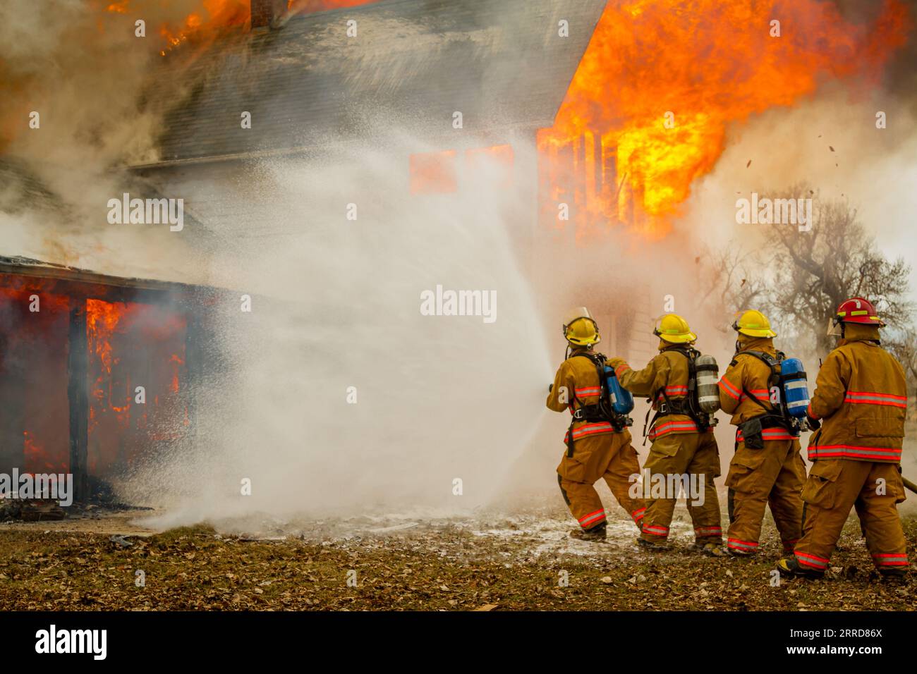 quattro vigili del fuoco che avanzano su un fuoco Foto Stock