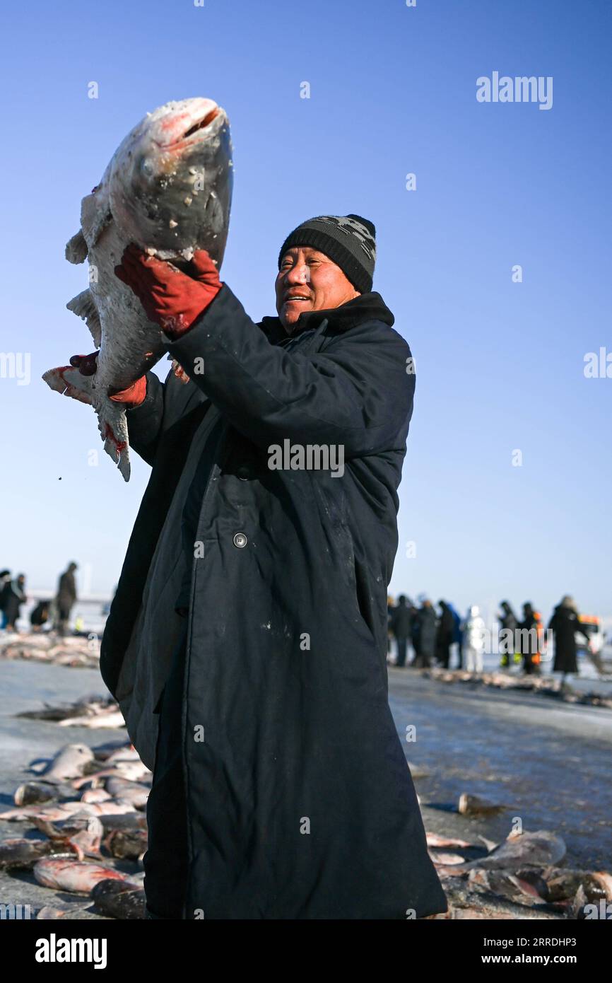 211227 -- SONGYUAN, 27 dicembre 2021 -- Un pescatore mostra un pesce appena pescato sul lago Chagan nella città di Songyuan, nella provincia di Jilin della Cina nordorientale, 26 dicembre 2021. Per secoli, pescatori e donne che vivono sul lago hanno mantenuto viva la tradizione della pesca sul ghiaccio -- perforando a mano attraverso il ghiaccio spesso e mettendo reti sotto per pescare. La tecnica è stata elencata come una forma a livello nazionale di patrimonio culturale immateriale. CHINA-JILIN-SONGYUAN-CHAGAN LAKE-WINTER FISHING CN YANXLINYUN PUBLICATIONXNOTXINXCHN Foto Stock