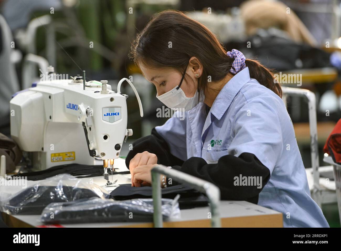 220112 -- MOYU, 12 gennaio 2022 -- Un membro del personale lavora in una fabbrica di abbigliamento nel parco industriale integrato nella contea di Moyu di Hotan, nella regione autonoma di Xinjiang Uygur della Cina nord-occidentale, 11 gennaio 2022. Situata sull'orlo meridionale del deserto di Taklimakan, Moyu era una volta una contea impoverita con poca terra coltivabile e debole fondazione industriale. Negli ultimi anni, la contea di Moyu ha fatto sforzi per attrarre investimenti come incentivo dello sviluppo industriale, ottimizza costantemente la struttura industriale e costruisce un parco industriale integrato con l'intera catena industriale di calze ed elettroni Foto Stock