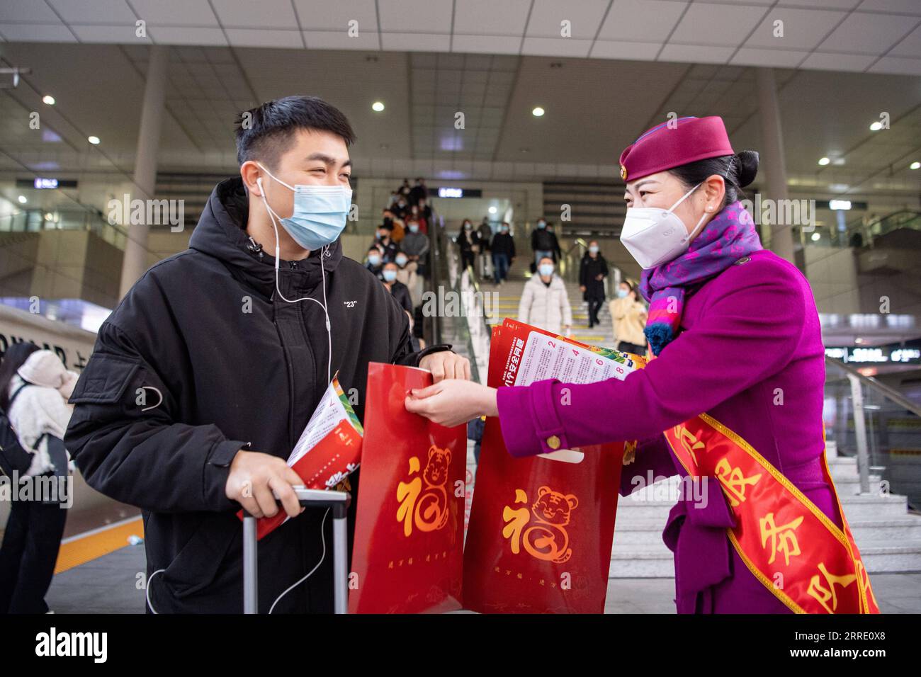 220117 -- CHONGQING, 17 gennaio 2022 -- Un membro dello staff distribuisce regali di Capodanno impressi con il carattere cinese fu , che significa buona fortuna in inglese, a un passeggero della stazione ferroviaria nord di Chongqing a Chongqing, nel sud-ovest della Cina, 17 gennaio 2022. La stagione turistica del Festival di primavera 2022 della Cina dovrebbe vedere 1,18 miliardi di viaggi passeggeri, in aumento del 35,6% anno dopo anno, ma 20,3% in meno rispetto a quello del 2020, ha detto il Ministero dei trasporti. La stagione dei viaggi di 40 giorni, nota anche come chunyun, ha dato il via lunedì e molte persone si recheranno per riunirsi con le loro famiglie per il Capodanno lunare, o il Foto Stock