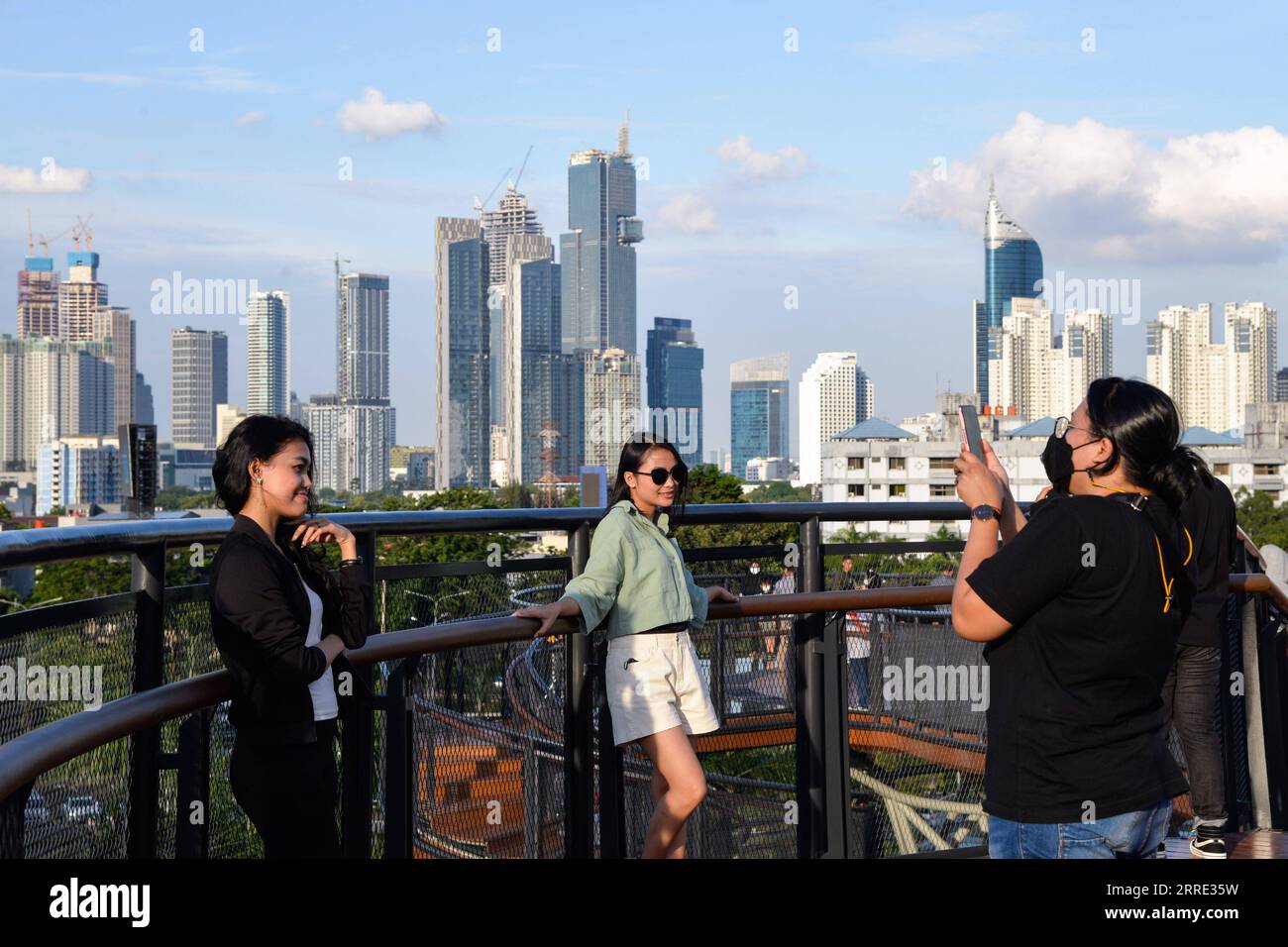 220123 -- GIACARTA, 23 gennaio 2022 -- la gente posa per delle foto sullo Skywalk del Senayan Park a Giacarta, Indonesia, 23 gennaio 2022. Il 18 gennaio i legislatori indonesiani hanno approvato una legge sul trasferimento della capitale della nazione sull'isola di Kalimantan, che il paese confina con la Malesia e il Brunei, dall'isola più popolata di Giava. Nusantara, che la nuova capitale è chiamata, sarà costruita in due distretti del Kalimantan orientale: Penajam Paser Utara e Kutai Kartanegara. Si prevede che occuperà circa 256.000 ettari di terreno. Nusantara servirà come centro del governo, mentre Giacarta W Foto Stock