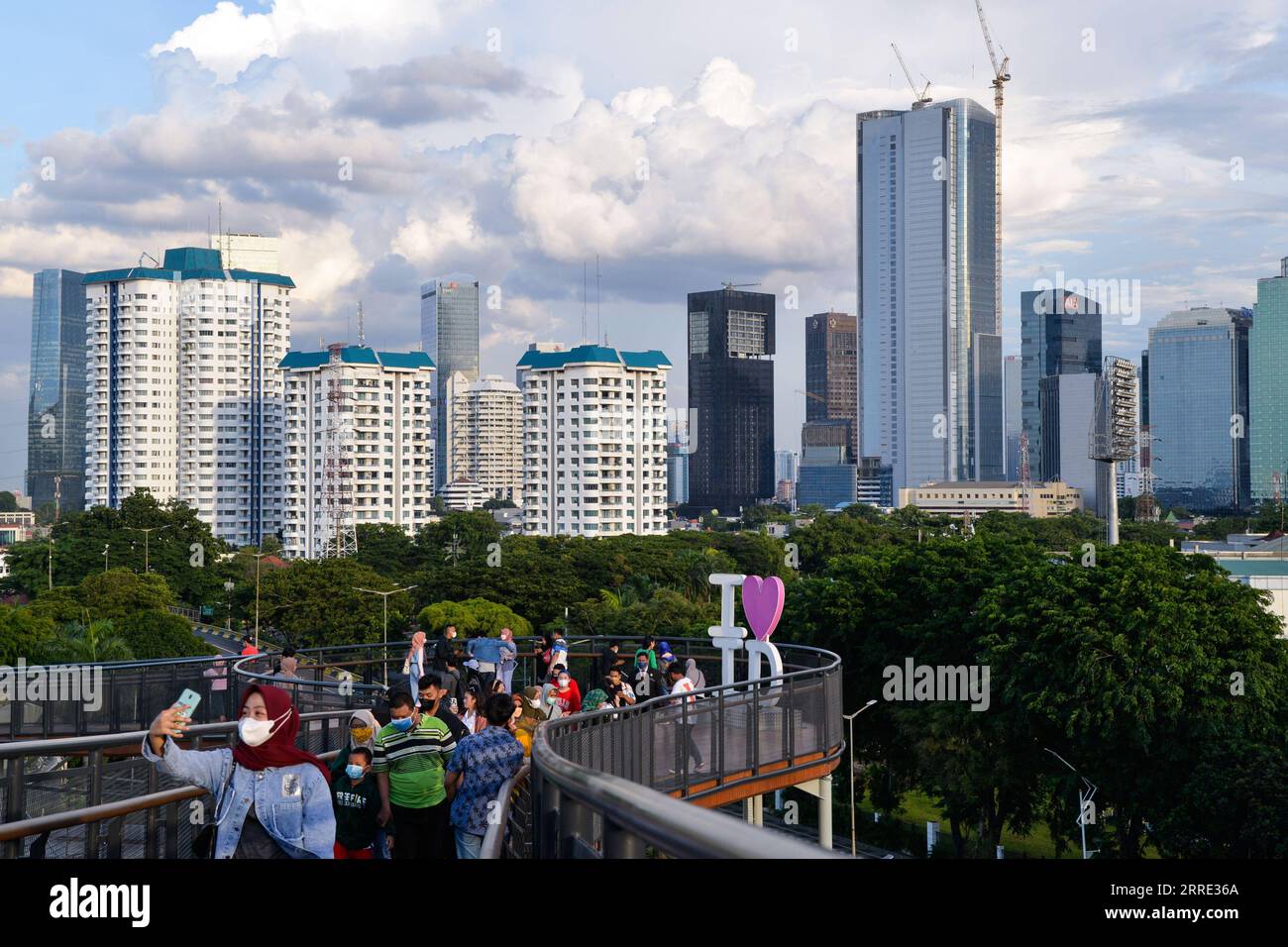 220123 -- GIACARTA, 23 gennaio 2022 -- la gente gode di una vista sulla città sulla passerella sopraelevata del Senayan Park a Giacarta, Indonesia, 23 gennaio 2022. Il 18 gennaio i legislatori indonesiani hanno approvato una legge sul trasferimento della capitale della nazione sull'isola di Kalimantan, che il paese confina con la Malesia e il Brunei, dall'isola più popolata di Giava. Nusantara, che la nuova capitale è chiamata, sarà costruita in due distretti del Kalimantan orientale: Penajam Paser Utara e Kutai Kartanegara. Si prevede che occuperà circa 256.000 ettari di terreno. Nusantara servirà come centro del governo, mentre Giacarta W Foto Stock