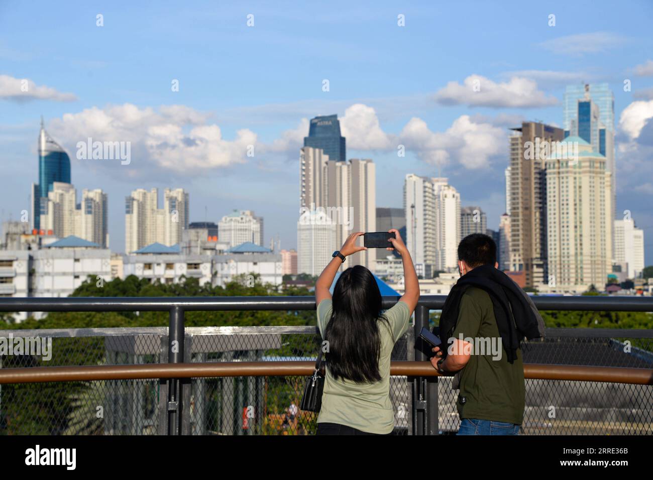 220123 -- GIACARTA, 23 gennaio 2022 -- le persone scattano foto sullo Skywalk del Senayan Park a Giacarta, Indonesia, 23 gennaio 2022. Il 18 gennaio i legislatori indonesiani hanno approvato una legge sul trasferimento della capitale della nazione sull'isola di Kalimantan, che il paese confina con la Malesia e il Brunei, dall'isola più popolata di Giava. Nusantara, che la nuova capitale è chiamata, sarà costruita in due distretti del Kalimantan orientale: Penajam Paser Utara e Kutai Kartanegara. Si prevede che occuperà circa 256.000 ettari di terreno. Nusantara servirà come centro del governo, mentre Giacarta wou Foto Stock