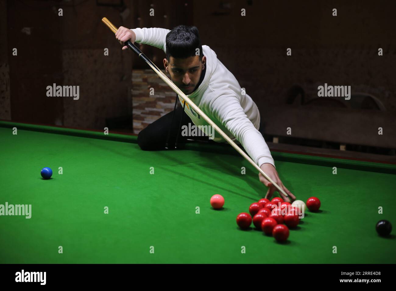 220126 -- GAZA, 26 gennaio 2022 -- il giovane palestinese Ahmed Nasr gioca a snooker all'interno di un club sportivo locale nella città meridionale di Rafah, nella Striscia di Gaza, il 26 gennaio 2022. Nasr, 22 anni, ha imparato a giocare a snooker e a biliardo da suo padre, poi ha imparato le regole del gioco attraverso i video di YouTube. Recentemente ha vinto il primo posto nel campionato di snooker della Striscia di Gaza, che lo ha qualificato per il campionato di classifica a livello della squadra palestinese. Foto di Khaled Omar/Xinhua SPMIDEAST-GAZA-RAFAH-SNOOKER EmadxDrimly PUBLICATIONxNOTxINxCHN Foto Stock