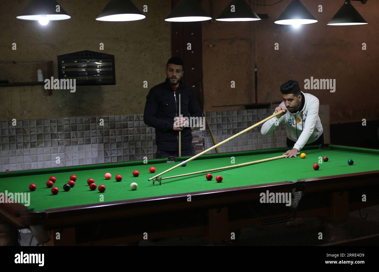 220126 -- GAZA, 26 gennaio 2022 -- il giovane palestinese Ahmed Nasr R gioca a snooker all'interno di un club sportivo locale nella città meridionale di Rafah, nella Striscia di Gaza, il 26 gennaio 2022. Nasr, 22 anni, ha imparato a giocare a snooker e a biliardo da suo padre, poi ha imparato le regole del gioco attraverso i video di YouTube. Recentemente ha vinto il primo posto nel campionato di snooker della Striscia di Gaza, che lo ha qualificato per il campionato di classifica a livello della squadra palestinese. Foto di Khaled Omar/Xinhua SPMIDEAST-GAZA-RAFAH-SNOOKER EmadxDrimly PUBLICATIONxNOTxINxCHN Foto Stock
