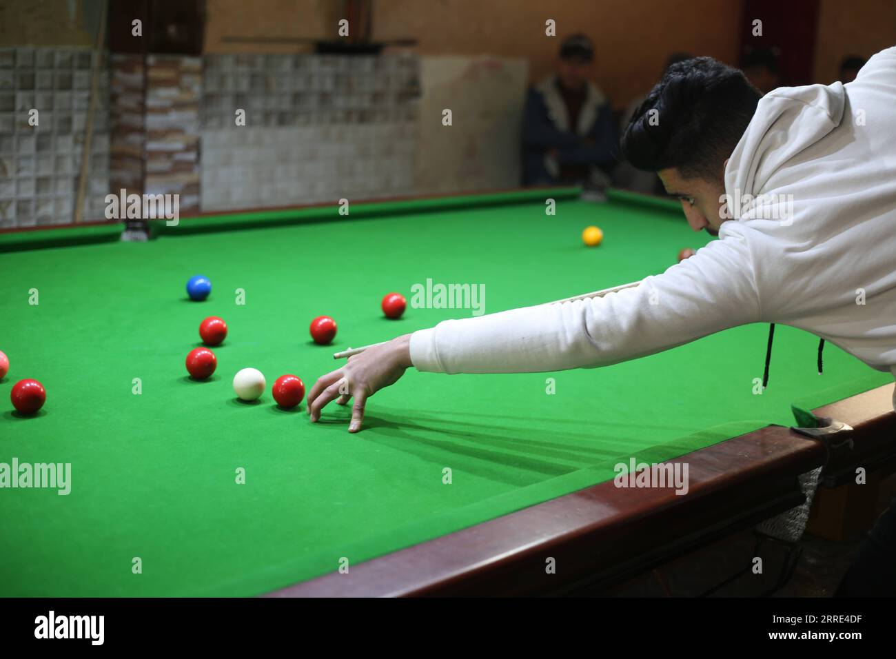 220126 -- GAZA, 26 gennaio 2022 -- il giovane palestinese Ahmed Nasr gioca a snooker all'interno di un club sportivo locale nella città meridionale di Rafah, nella Striscia di Gaza, il 26 gennaio 2022. Nasr, 22 anni, ha imparato a giocare a snooker e a biliardo da suo padre, poi ha imparato le regole del gioco attraverso i video di YouTube. Recentemente ha vinto il primo posto nel campionato di snooker della Striscia di Gaza, che lo ha qualificato per il campionato di classifica a livello della squadra palestinese. Foto di Khaled Omar/Xinhua SPMIDEAST-GAZA-RAFAH-SNOOKER EmadxDrimly PUBLICATIONxNOTxINxCHN Foto Stock