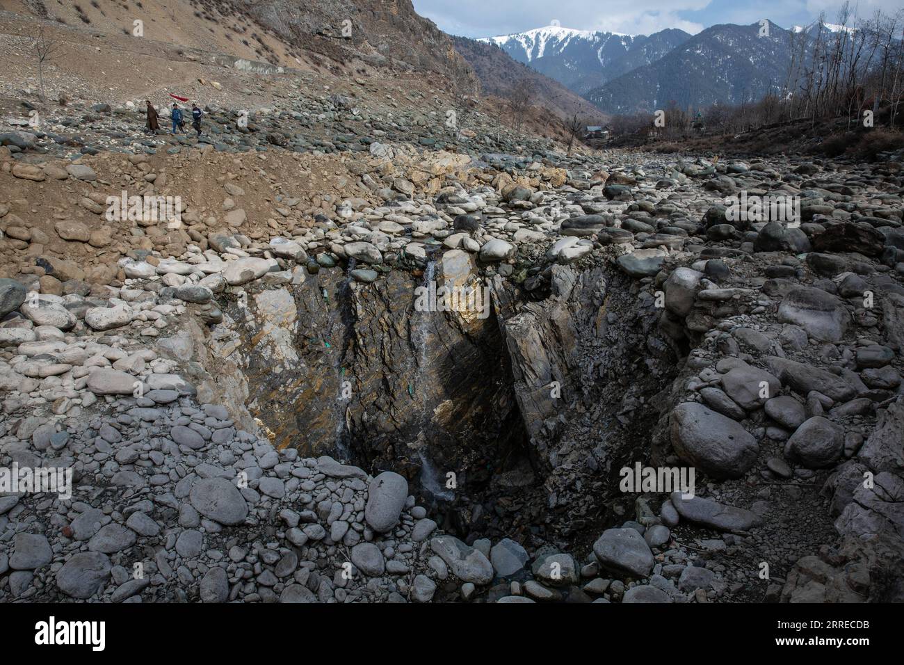 220218 -- SRINAGAR, 18 febbraio 2022 -- la gente cammina vicino a una dolina verticale che si è sviluppata nel mezzo di un letto di fiume in un villaggio nel distretto di Anantnag, circa 94 km a sud della città di Srinagar, la capitale estiva del Kashmir controllato dagli indiani, 18 febbraio 2022. Una dolina verticale che si è sviluppata nel mezzo di un letto di fiume ha divorato un flusso d'acqua dolce nel Kashmir controllato dagli indiani, hanno detto i funzionari giovedì. La dolina ha prosciugato tutta la corrente d'acqua in essa e ha lasciato asciutta la parte a valle, uccidendo in gran numero i pesci di trota. Ha anche causato danni incommensurabili Foto Stock