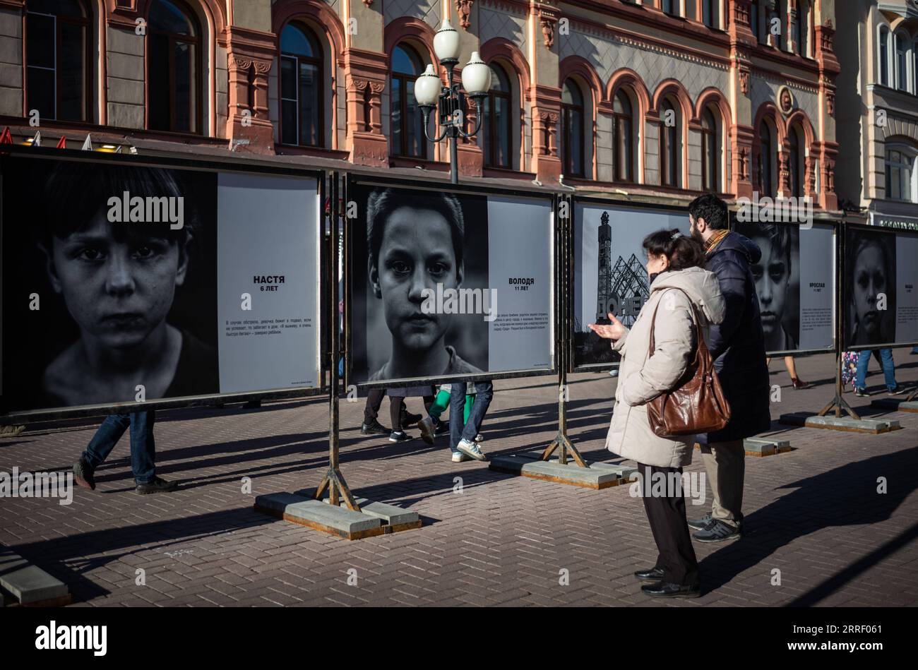 220321 -- MOSCA, 21 marzo 2022 -- la gente guarda le opere della mostra fotografica Guarda negli occhi di Donbass in via Arbat a Mosca, Russia, il 20 marzo 2022. RUSSIA-MOSCA-DONBASS-MOSTRA FOTOGRAFICA BaixXueqi PUBLICATIONxNOTxINxCHN Foto Stock