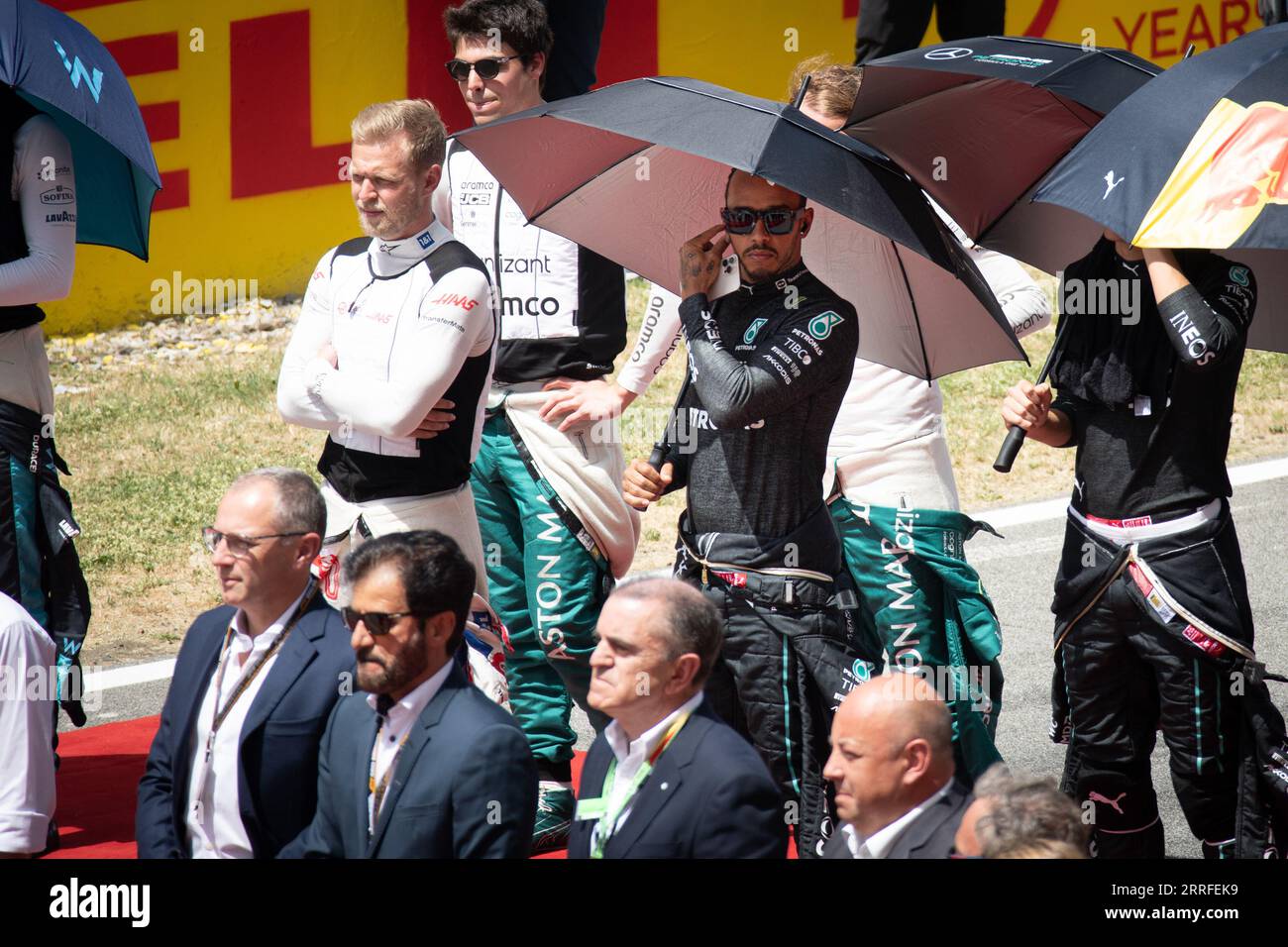 Il campione di F1 Lewis Hamilton indossa la sua tuta da gara, tenendo un ombrello durante un evento pre-gara, incapsulando un momento di calma prima dello stor delle corse Foto Stock