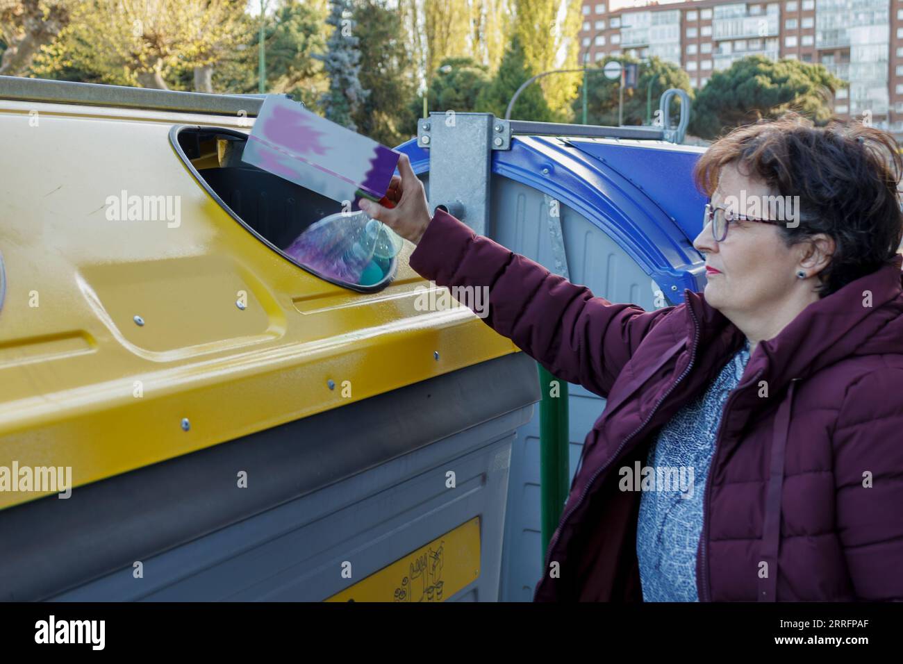 donna che getta plastica in un contenitore giallo specifico per il riciclaggio e la tutela dell'ambiente Foto Stock