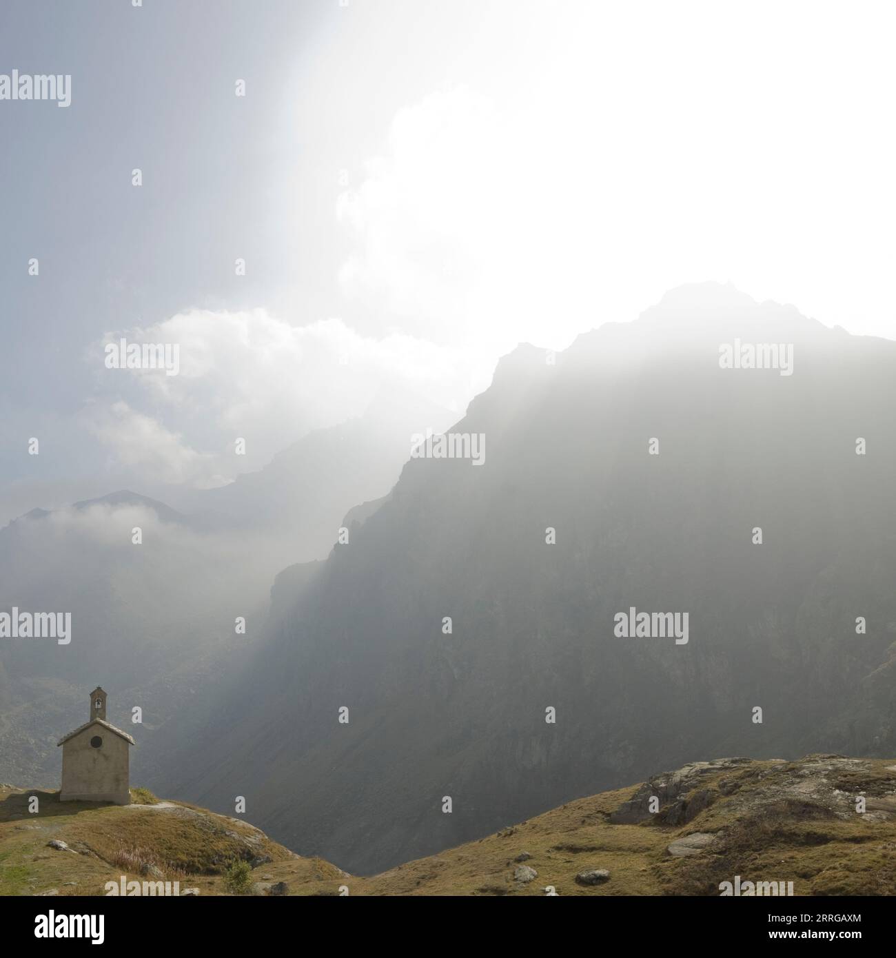 Chiesetta arroccata in montagna con i raggi del sole Foto Stock